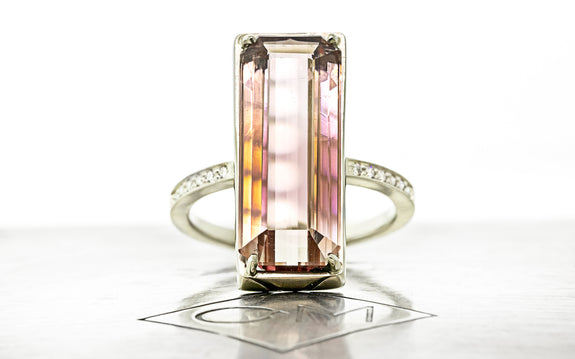 10 carat emerald cut pink tourmaline ring set in 14 karat white gold with six white pavé diamonds on each shoulder front view on Chinchar Maloney metal plate