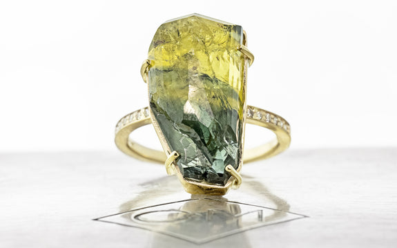 19.32 carat double cut green and yellow sapphire ring in 14 karat yellow gold with six white pavé on each shoulder front view on Chinchar Maloney metal plate