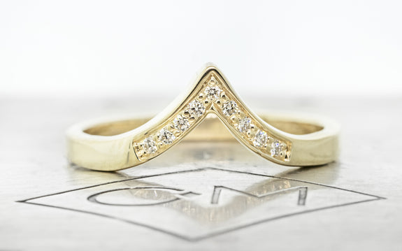 14 karat yellow gold Summit shadow band with 9 white pavé diamonds front view on Chinchar Maloney metal plate
