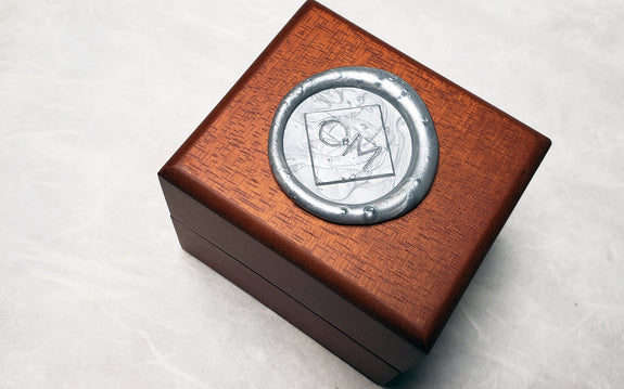 wooden Chinchar Maloney jewelry box with sealing wax logo on white background