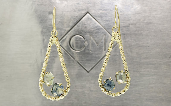 14 karat yellow gold drop style earrings with one light blue and one darker blue Montana sapphire totaling 2.26 carats on Chinchar Maloney metal plate