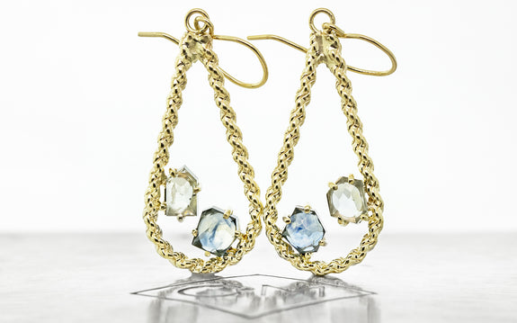 14 karat yellow gold drop style earrings with one light blue and one darker blue Montana sapphire totaling 2.26 carats on Chinchar Maloney metal plate