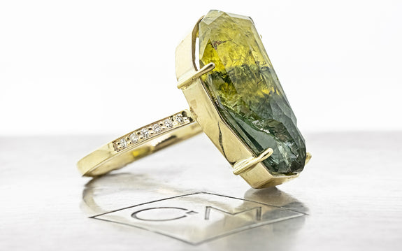 19.32 carat double cut green and yellow sapphire ring in 14 karat yellow gold with six white pavé on each shoulder side view on Chinchar Maloney metal plate